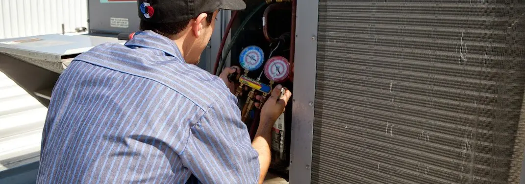 HVAC technician servicing a condenser unit in Waterloo